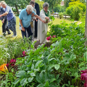 Vergiss-mein-nicht-Gottesdienst 2023 in der Emmauskirche Feldkirchen-Westerham Besucher streuen unter Anleitung von Monika Langer Samen in ein vorbereitetes Blumenbeet. Im Hintergrund Pfarrerin Susanne Franke.